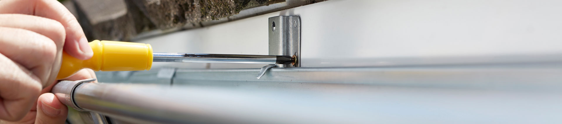 man drilling gutters onto a home